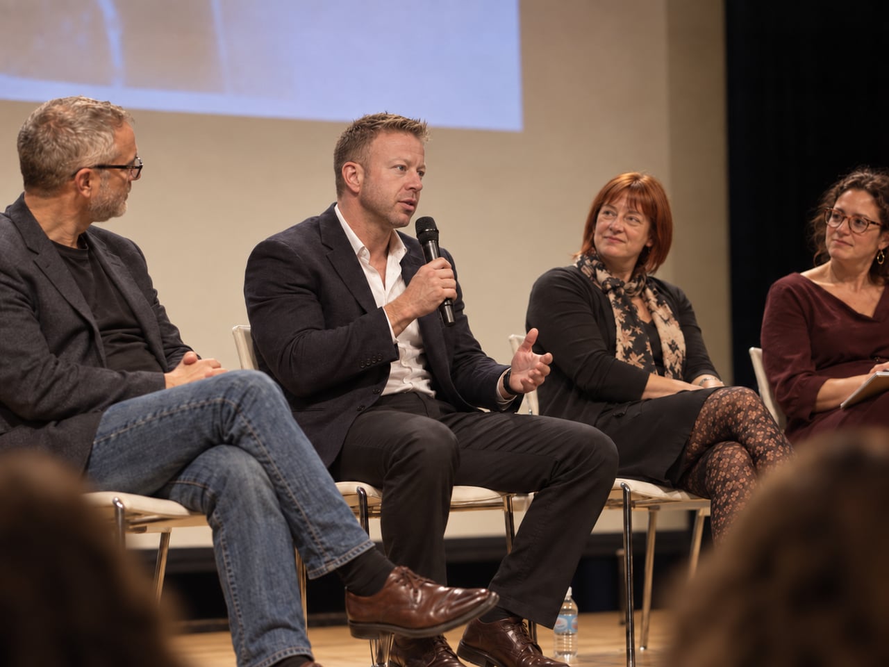 Edited/generated editorial panel discussion scene with Garrit holding a microphone.